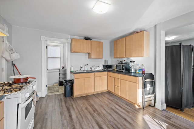 kitchen with light brown cabinetry, sink, light hardwood / wood-style floors, white gas range oven, and black fridge