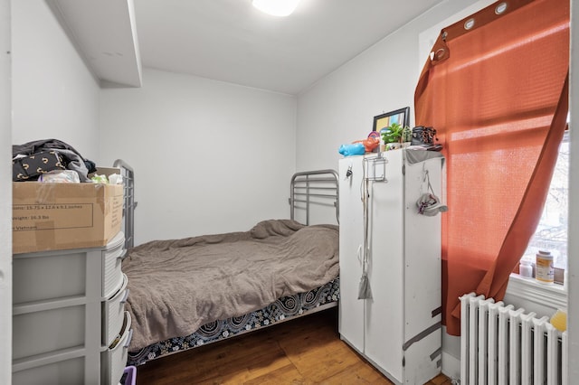 bedroom with hardwood / wood-style floors and radiator heating unit