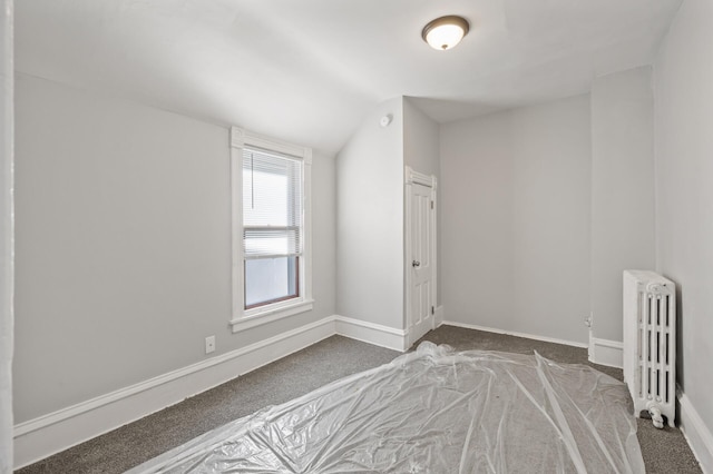 carpeted empty room with radiator and vaulted ceiling