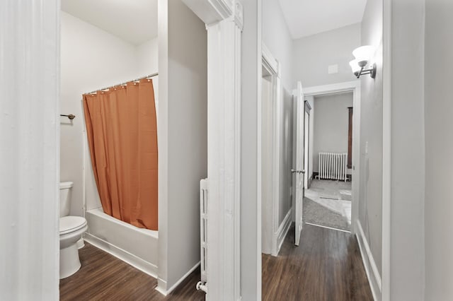 bathroom featuring radiator, hardwood / wood-style floors, toilet, and shower / bath combo with shower curtain