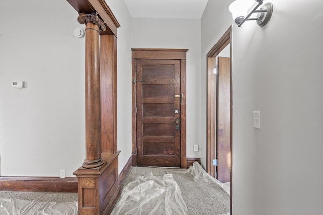 hallway featuring decorative columns and light carpet