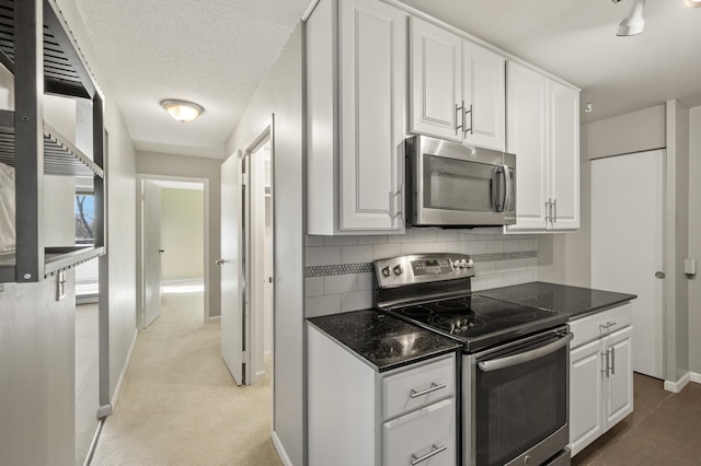 kitchen with stainless steel appliances, a textured ceiling, white cabinets, and backsplash