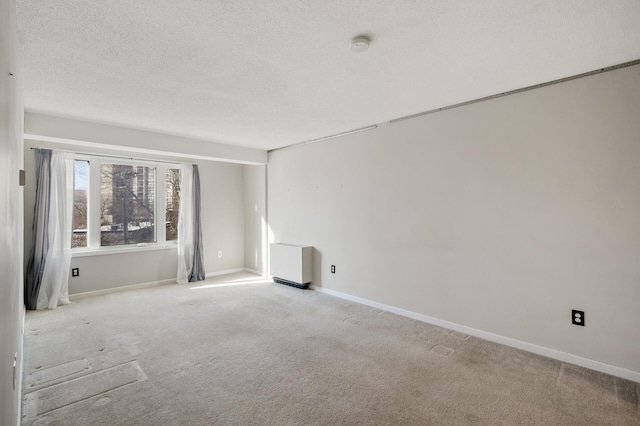 unfurnished room with light colored carpet and a textured ceiling