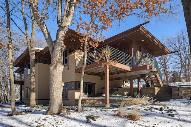 snow covered back of property with a deck