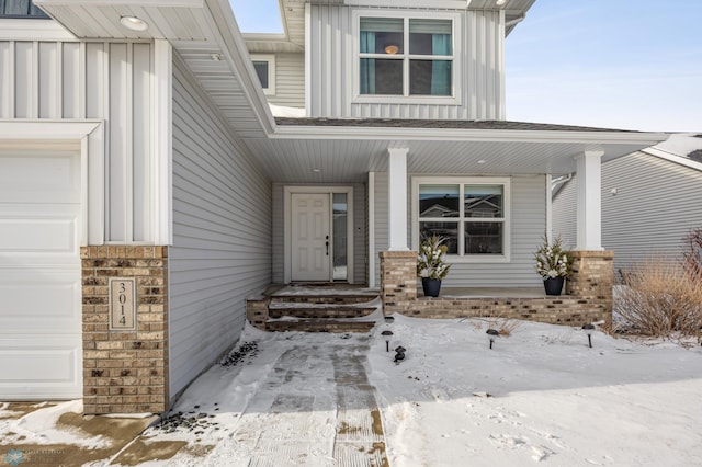 snow covered property entrance with a garage