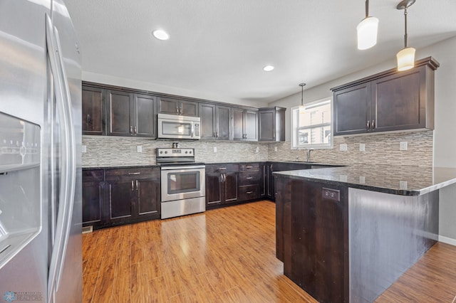 kitchen with stainless steel appliances, hanging light fixtures, and dark brown cabinetry