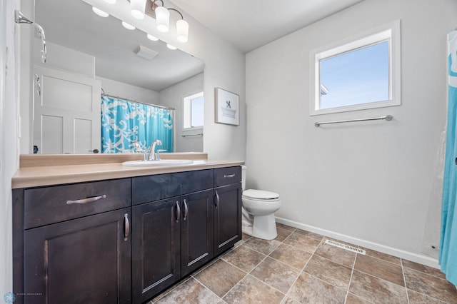 bathroom with plenty of natural light, toilet, and vanity