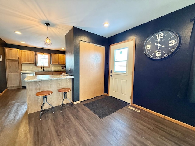 kitchen with pendant lighting, a kitchen breakfast bar, dark hardwood / wood-style floors, stainless steel dishwasher, and kitchen peninsula