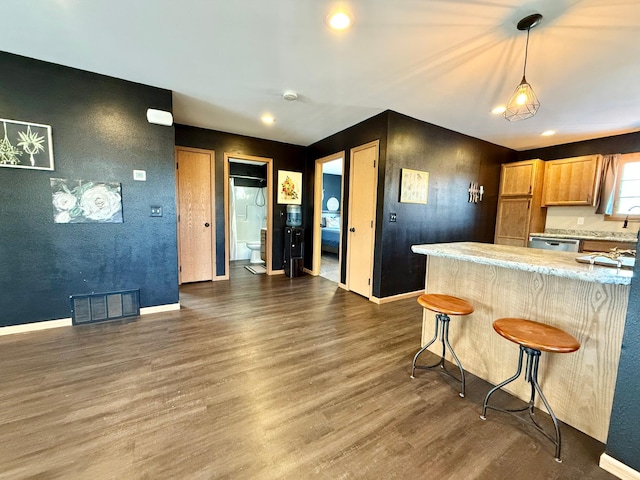 kitchen featuring a kitchen bar, stainless steel dishwasher, dark hardwood / wood-style flooring, kitchen peninsula, and pendant lighting