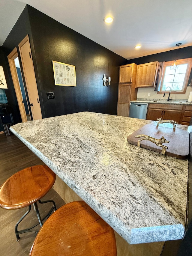 kitchen with stainless steel dishwasher, dark hardwood / wood-style flooring, sink, and a breakfast bar area