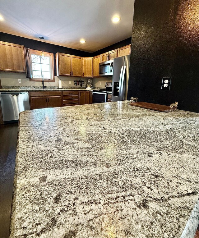 kitchen with light stone counters, sink, and stainless steel appliances