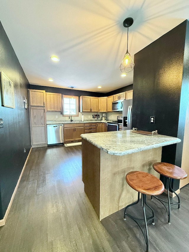 kitchen with pendant lighting, appliances with stainless steel finishes, a kitchen breakfast bar, dark hardwood / wood-style floors, and light stone countertops