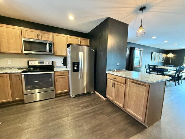 kitchen featuring dark wood-type flooring, decorative light fixtures, kitchen peninsula, stainless steel appliances, and light stone countertops