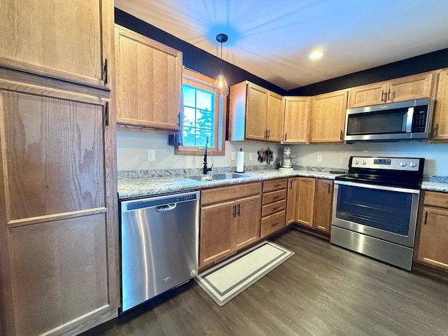 kitchen featuring appliances with stainless steel finishes, dark hardwood / wood-style floors, sink, hanging light fixtures, and light stone countertops