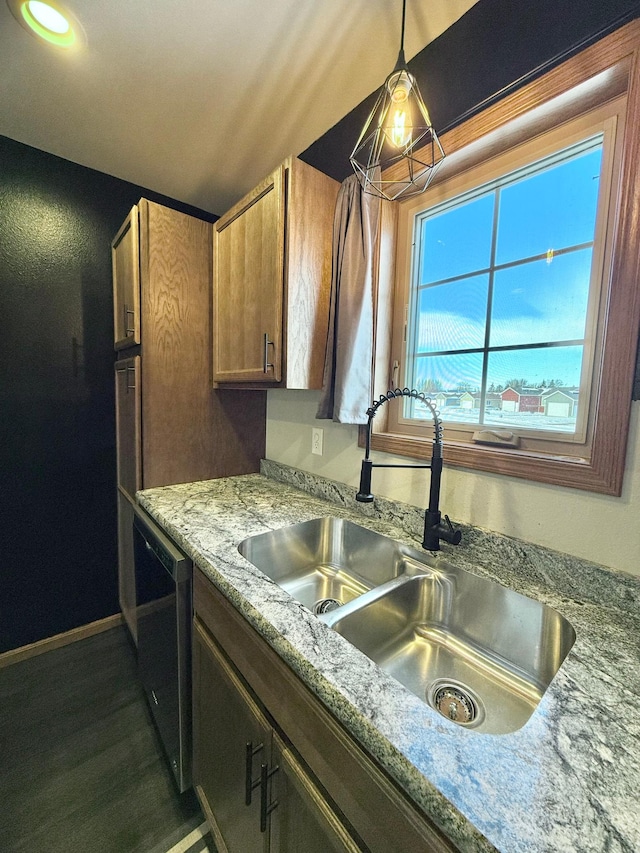 kitchen featuring pendant lighting, dishwashing machine, sink, and light stone countertops