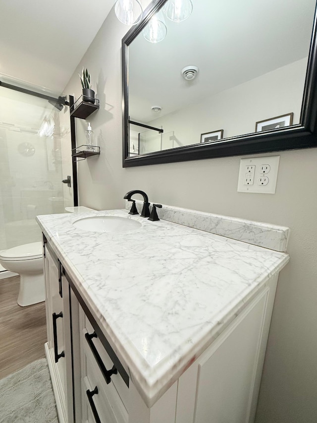 bathroom with vanity, wood-type flooring, toilet, and walk in shower