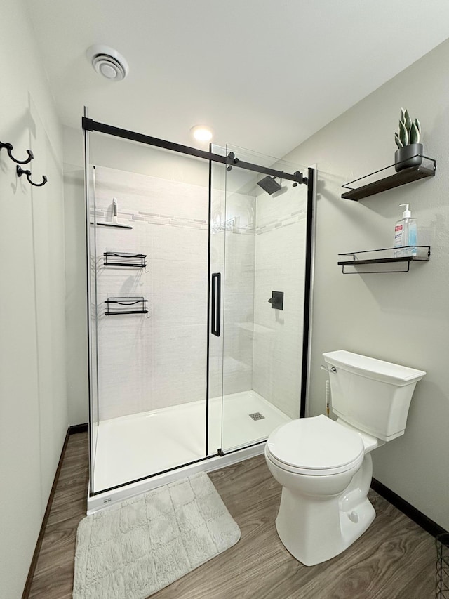 bathroom with hardwood / wood-style flooring, toilet, and walk in shower