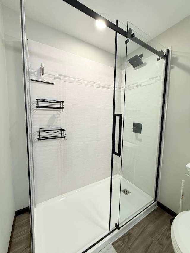 bathroom featuring hardwood / wood-style floors, an enclosed shower, and toilet