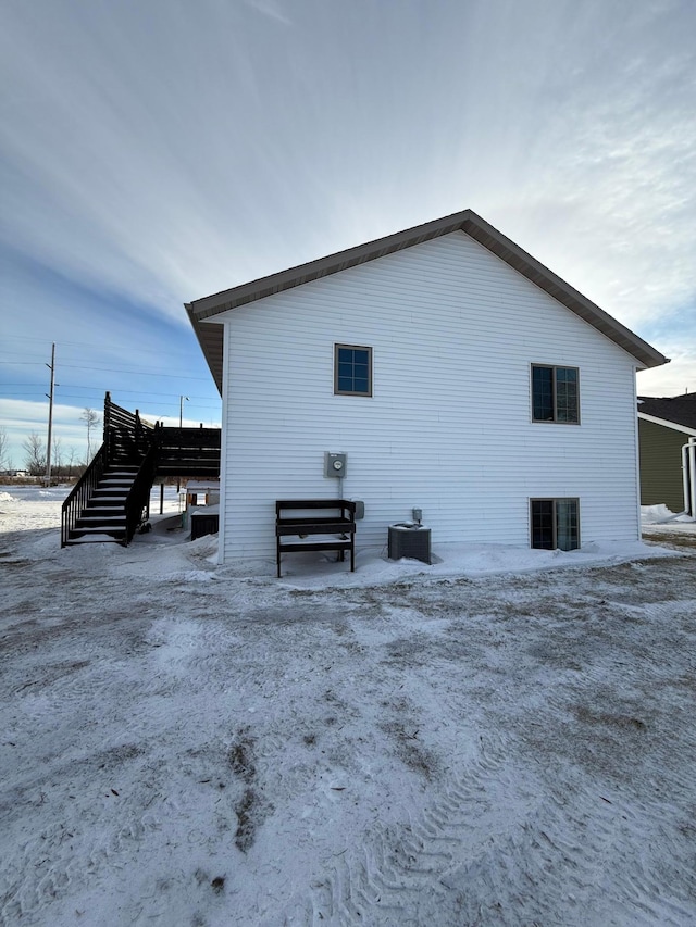 snow covered rear of property with central air condition unit