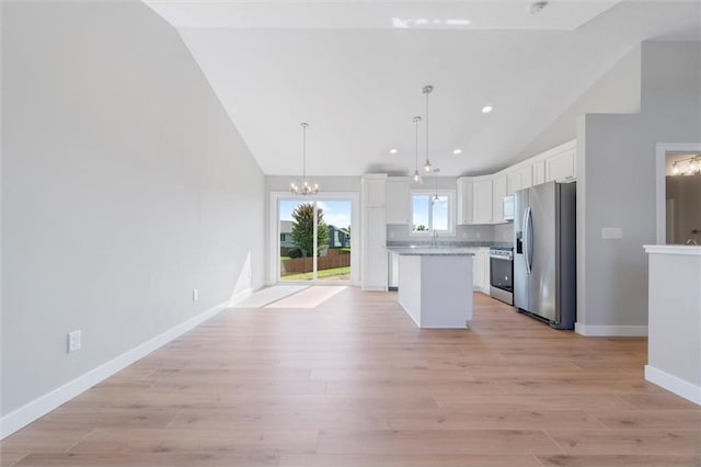 kitchen featuring decorative light fixtures, a center island, vaulted ceiling, stainless steel appliances, and white cabinets