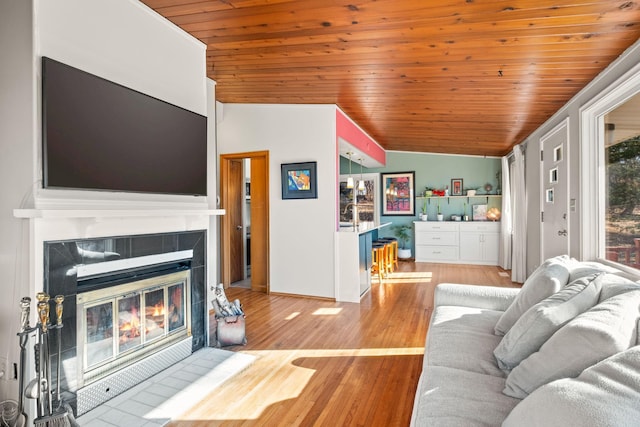 living room with wood ceiling, a fireplace, light hardwood / wood-style floors, and vaulted ceiling