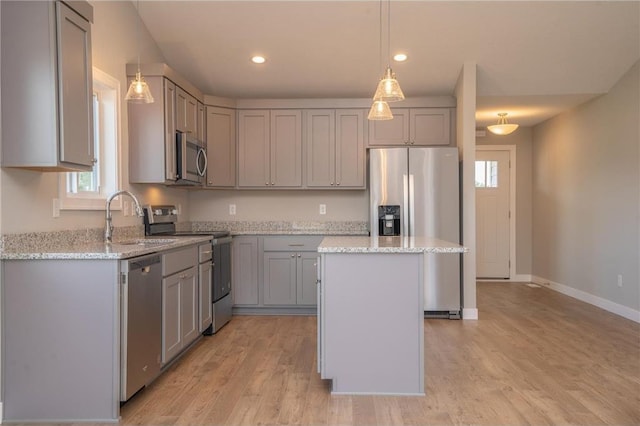 kitchen featuring light stone counters, gray cabinetry, appliances with stainless steel finishes, and a kitchen island