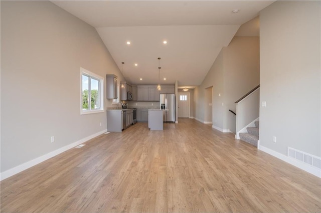 unfurnished living room featuring high vaulted ceiling, sink, and light wood-type flooring