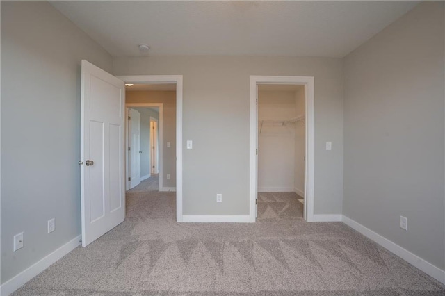 unfurnished bedroom featuring a spacious closet, light colored carpet, and a closet