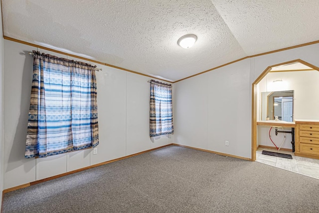 unfurnished bedroom featuring lofted ceiling, ornamental molding, a textured ceiling, and carpet