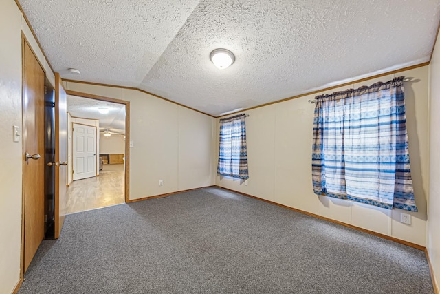 spare room with vaulted ceiling, carpet, a textured ceiling, and crown molding