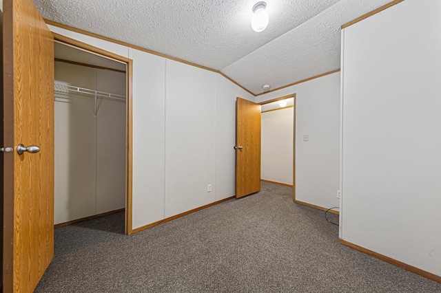 unfurnished bedroom with dark carpet, vaulted ceiling, a closet, and a textured ceiling