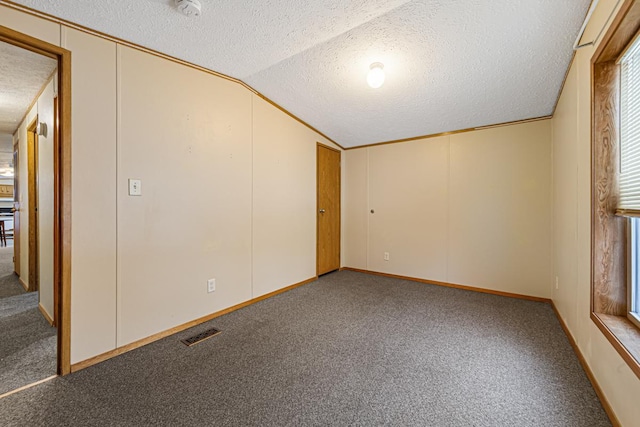 carpeted spare room with vaulted ceiling and a textured ceiling