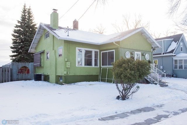 snow covered house featuring cooling unit