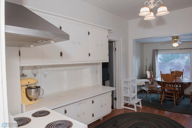 kitchen with dark hardwood / wood-style floors, range hood, hanging light fixtures, and white cabinets