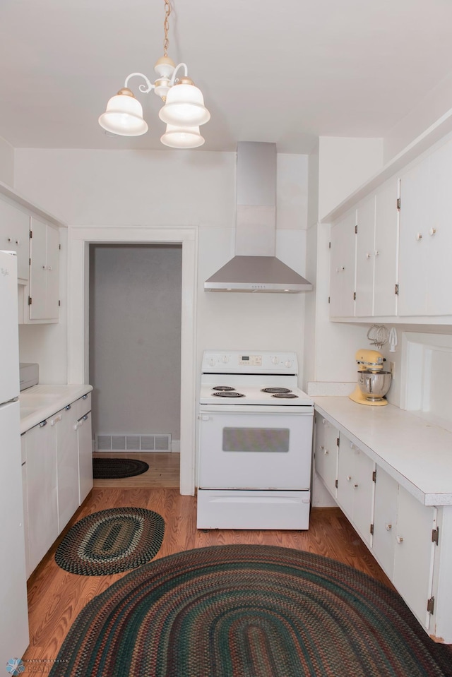 kitchen with decorative light fixtures, white cabinetry, dark wood-type flooring, white appliances, and wall chimney exhaust hood