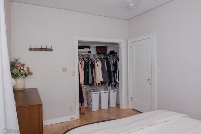 bedroom with ornamental molding, light hardwood / wood-style floors, and a closet