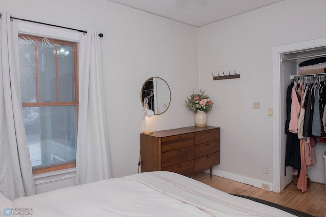 bedroom with hardwood / wood-style floors, ornamental molding, and a closet