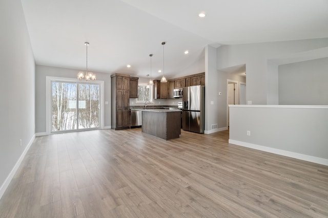 kitchen with a kitchen island, appliances with stainless steel finishes, an inviting chandelier, decorative light fixtures, and light wood-type flooring