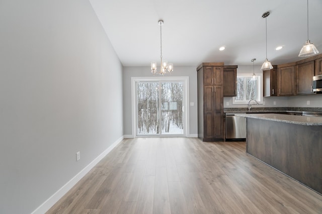 kitchen with an inviting chandelier, dark brown cabinets, hanging light fixtures, stainless steel appliances, and light hardwood / wood-style floors