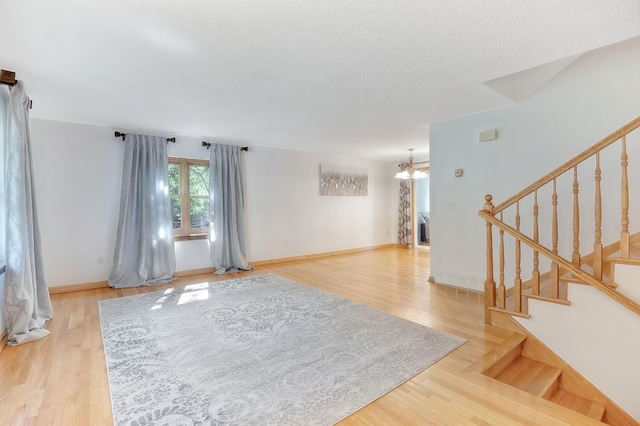 interior space with hardwood / wood-style floors, a textured ceiling, and a chandelier