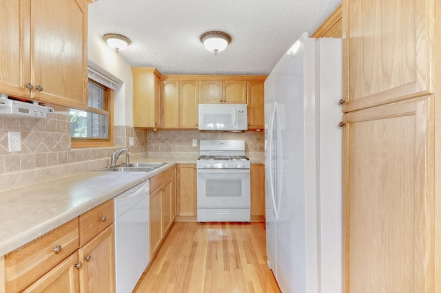 kitchen with sink, white appliances, light hardwood / wood-style floors, a textured ceiling, and decorative backsplash