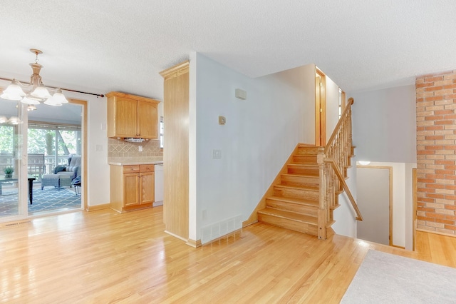 staircase with wood-type flooring, a chandelier, and a textured ceiling