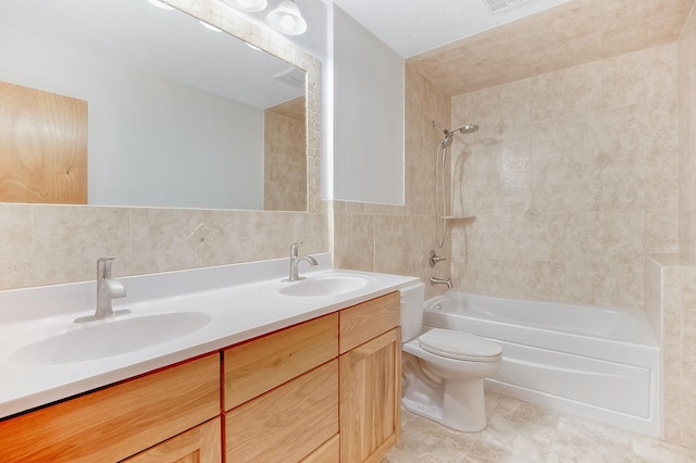 full bathroom featuring tile walls, tiled shower / bath combo, vanity, decorative backsplash, and toilet