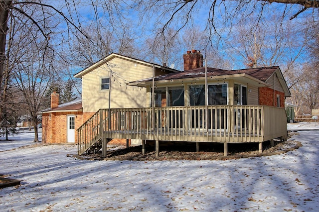 snow covered rear of property with a deck