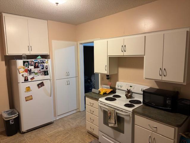 kitchen featuring white cabinetry, light tile patterned floors, a textured ceiling, and white appliances