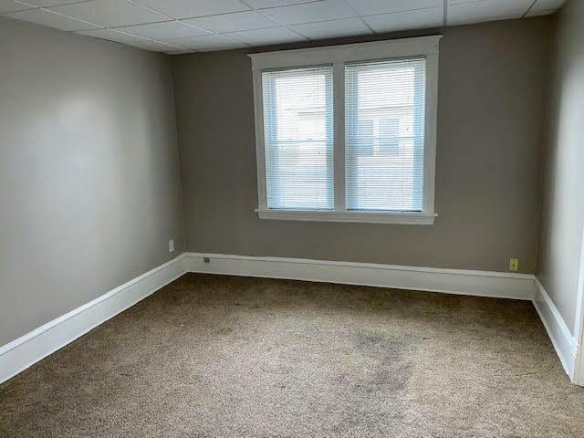 carpeted empty room featuring a drop ceiling