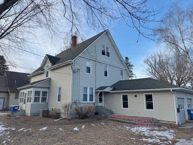 rear view of property with central AC and a garage