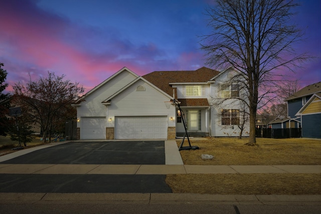 traditional home with aphalt driveway, brick siding, and an attached garage