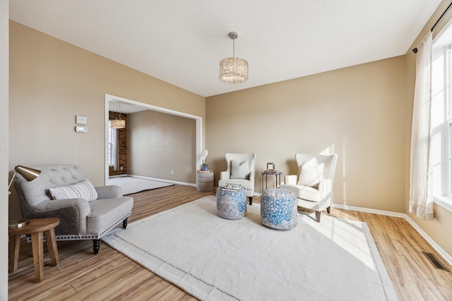 living area featuring baseboards, visible vents, and light wood finished floors