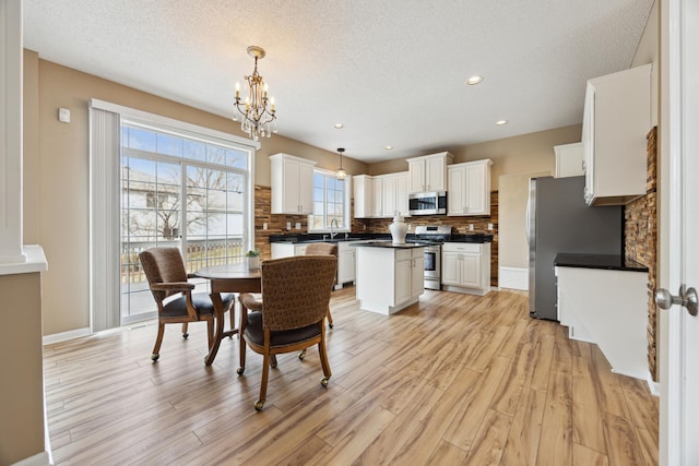 dining room featuring baseboards, a notable chandelier, light wood-style flooring, and a textured ceiling